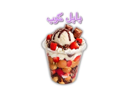 Tall plastic cup filled with layered fruit, granola, and whipped cream topped with chocolate drizzle and strawberries