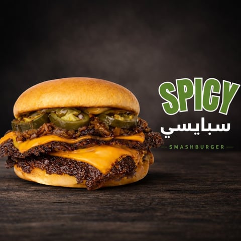 Spicy smashburger with melted cheese and caramelized onions on a toasted bun against dark background